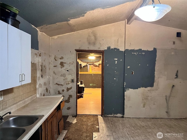 kitchen featuring lofted ceiling, tasteful backsplash, light countertops, and a sink