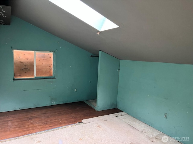 additional living space featuring vaulted ceiling with skylight and wood finished floors