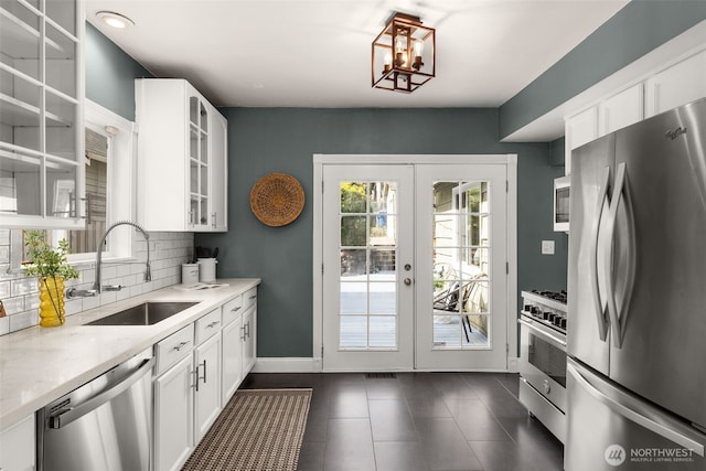 kitchen with backsplash, glass insert cabinets, french doors, stainless steel appliances, and a sink