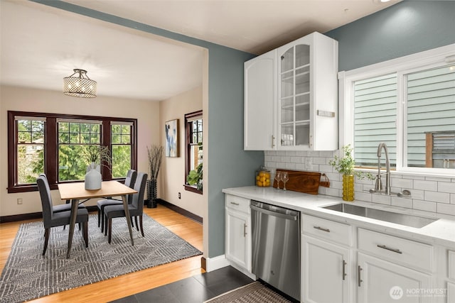 kitchen featuring a sink, decorative backsplash, glass insert cabinets, and dishwasher