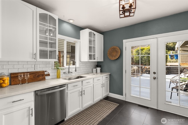 kitchen with dark tile patterned flooring, a sink, decorative backsplash, french doors, and dishwasher