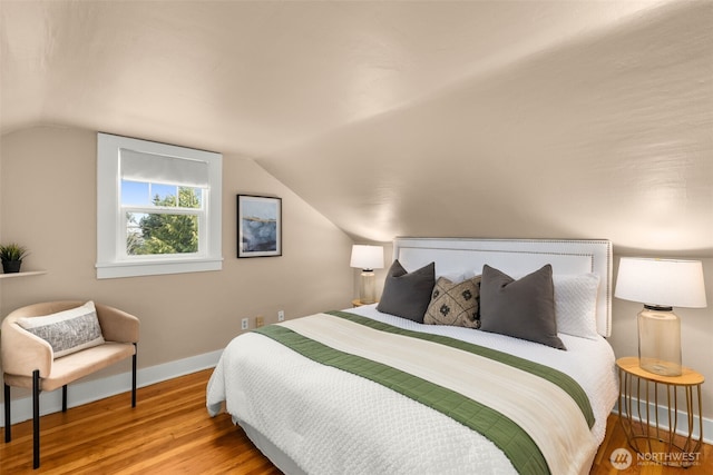 bedroom with baseboards, lofted ceiling, and wood finished floors