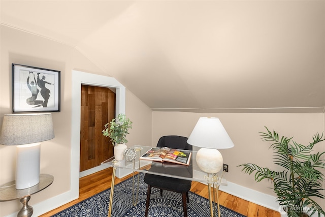 office area with baseboards, wood finished floors, and vaulted ceiling