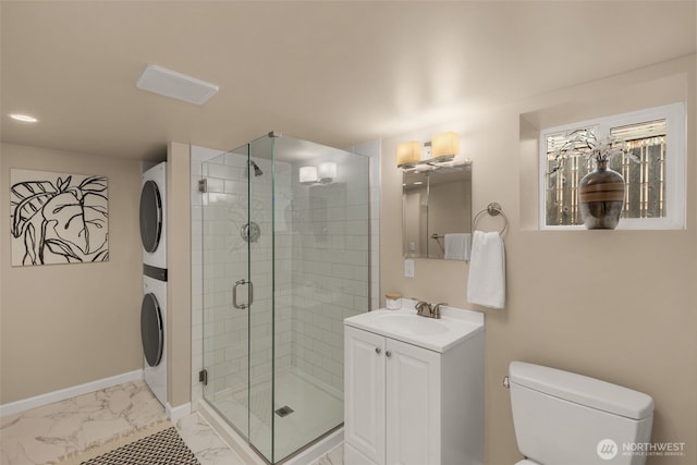 bathroom with baseboards, toilet, a stall shower, stacked washing maching and dryer, and marble finish floor