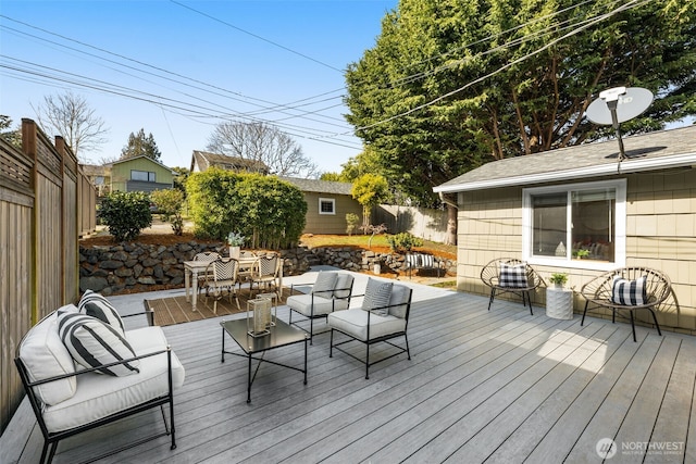 wooden deck with outdoor dining space, an outdoor living space, an outbuilding, and a fenced backyard