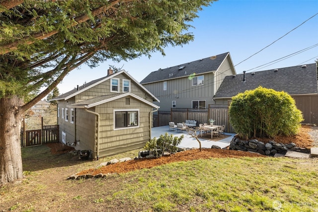 back of property with a yard, fence, a chimney, and a patio area