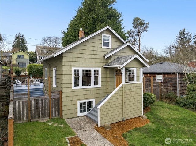 back of property with a yard, fence, and a chimney