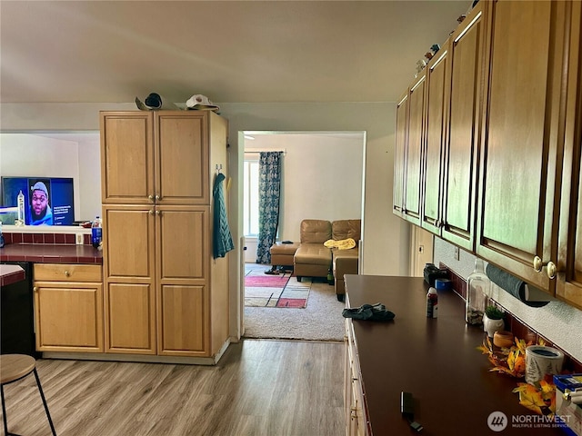 kitchen featuring light wood-type flooring, tile counters, and open floor plan