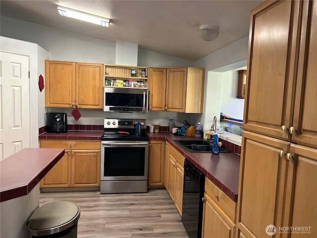 kitchen featuring a sink, light wood-style floors, vaulted ceiling, appliances with stainless steel finishes, and open shelves