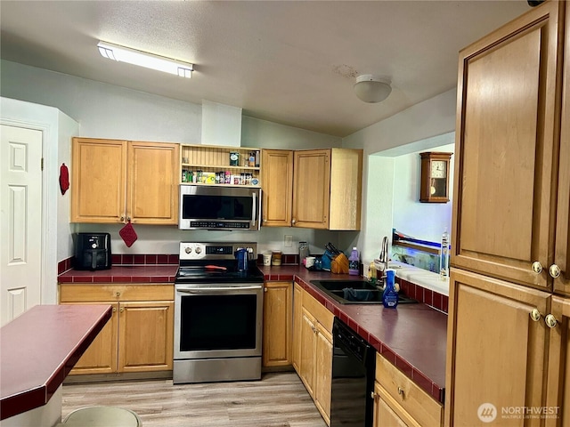 kitchen with tile counters, lofted ceiling, stainless steel appliances, light wood-type flooring, and open shelves