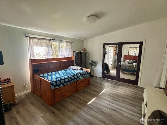 bedroom with vaulted ceiling, dark wood-style flooring, and french doors