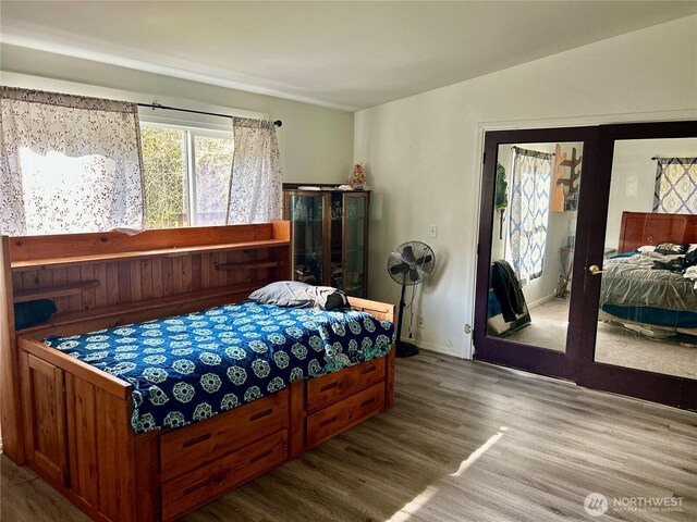 bedroom with baseboards, wood finished floors, and french doors