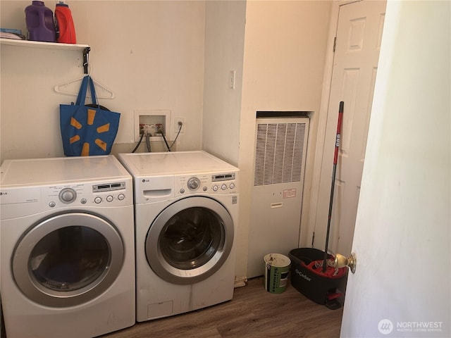 washroom featuring washing machine and dryer, laundry area, a heating unit, and wood finished floors