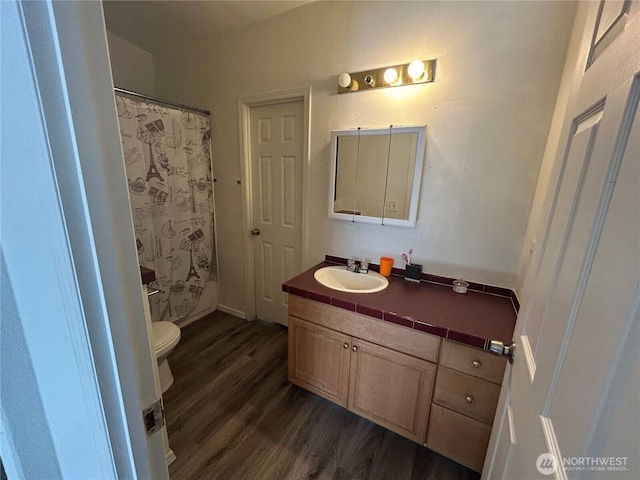 bathroom with toilet, a shower with shower curtain, wood finished floors, and vanity