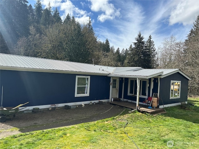 rear view of property featuring a porch, metal roof, and a lawn