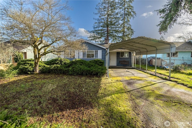 view of front of property featuring driveway, fence, and a detached carport