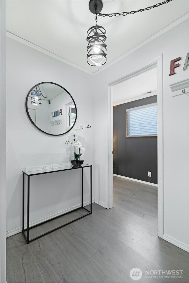 corridor featuring ornamental molding, wood finished floors, and baseboards