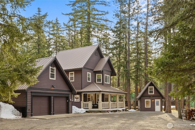 view of front of house with a garage, covered porch, driveway, and metal roof