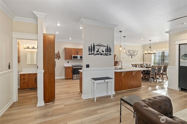 kitchen with light wood-style flooring, stainless steel appliances, an inviting chandelier, a breakfast bar area, and brown cabinetry