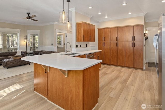 kitchen featuring a ceiling fan, brown cabinets, a breakfast bar, a sink, and open floor plan