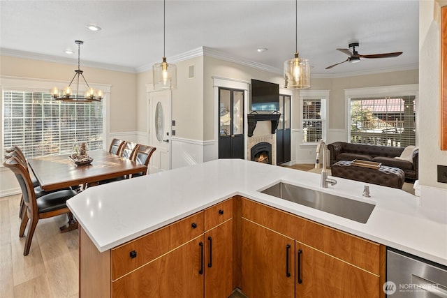 kitchen with a sink, a wainscoted wall, open floor plan, and light countertops