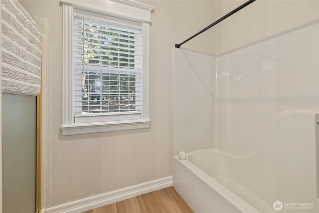 bathroom with tub / shower combination, baseboards, and wood finished floors