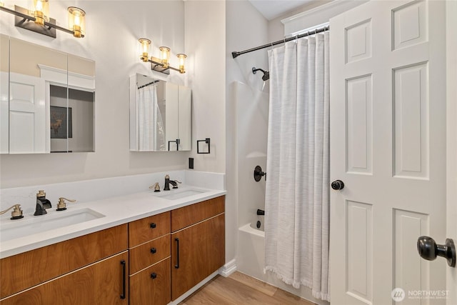 full bath featuring wood finished floors, shower / bathtub combination with curtain, double vanity, and a sink