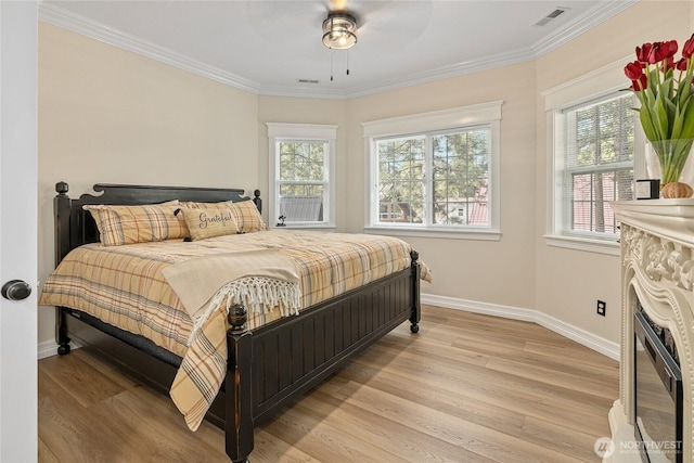 bedroom featuring visible vents, baseboards, light wood-style flooring, and ornamental molding