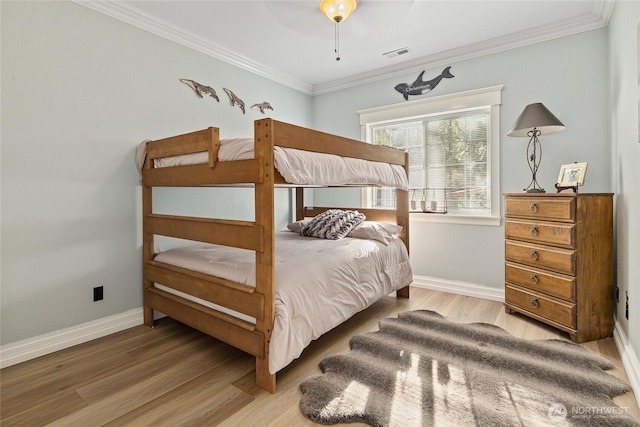 bedroom with crown molding, wood finished floors, visible vents, and baseboards