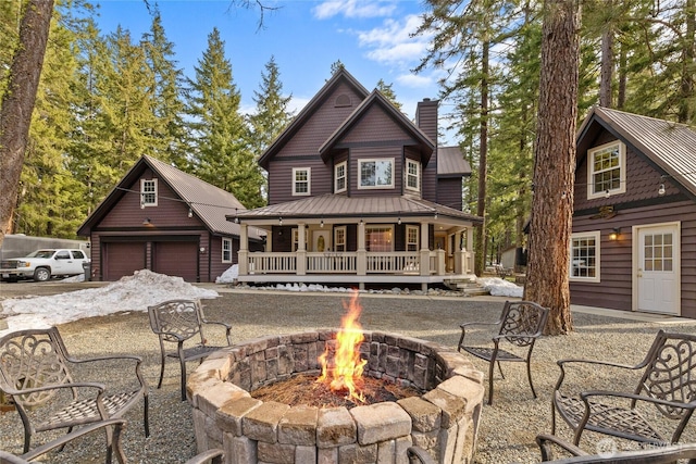 back of property featuring a standing seam roof, an outdoor fire pit, a garage, and metal roof