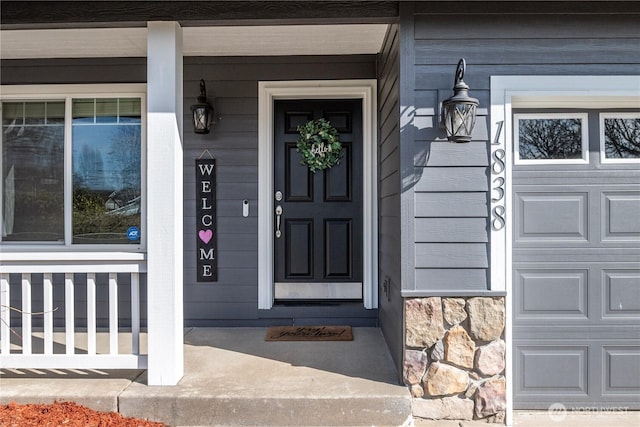 view of exterior entry with a garage and covered porch