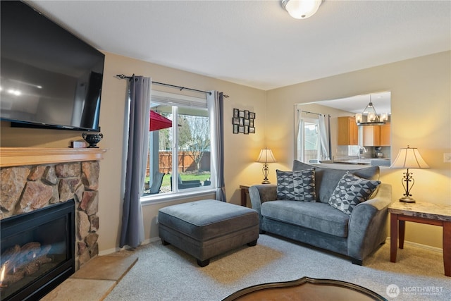 living area featuring carpet, a notable chandelier, a fireplace, and baseboards