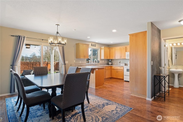 dining area with a chandelier, recessed lighting, wood finished floors, and baseboards