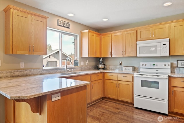 kitchen with a breakfast bar area, light brown cabinetry, a sink, white appliances, and a peninsula