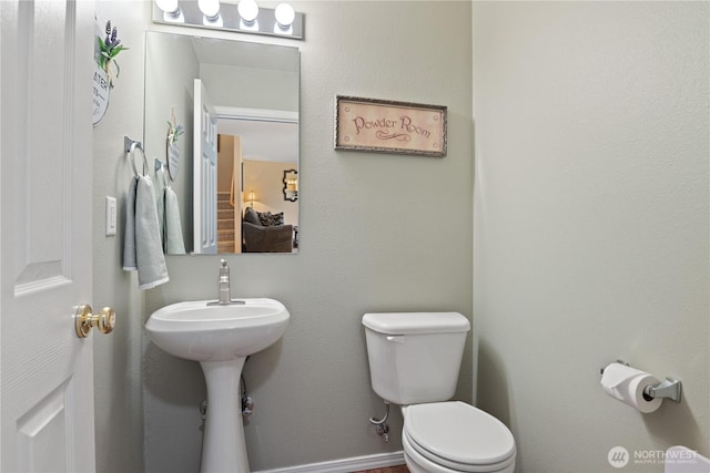 bathroom featuring baseboards and toilet