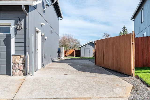 view of home's exterior with a garage, a patio, an outbuilding, fence, and a shed