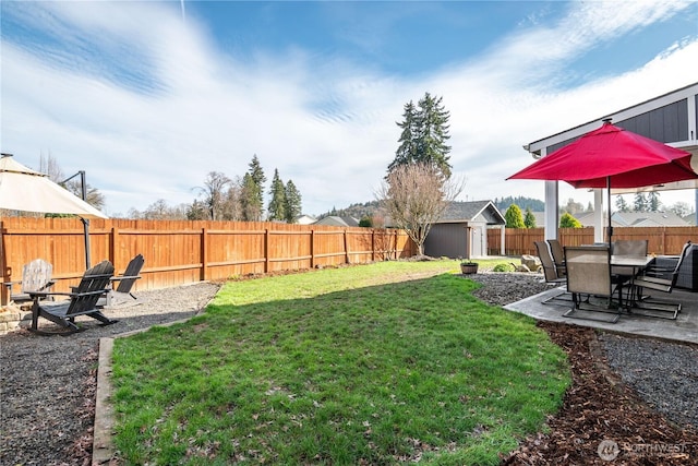 view of yard featuring an outbuilding, a patio, and a fenced backyard