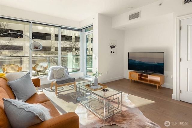 living area featuring visible vents, baseboards, and wood finished floors