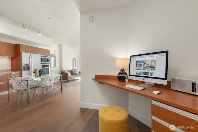 home office with dark wood-style floors, built in study area, rail lighting, and baseboards