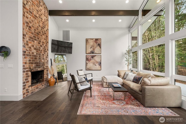 living area with baseboards, beam ceiling, a fireplace, a high ceiling, and wood finished floors