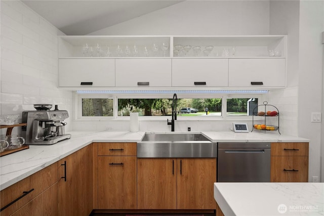 kitchen with a sink, lofted ceiling, light stone counters, decorative backsplash, and stainless steel dishwasher