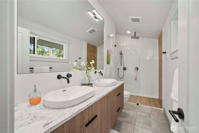 bathroom featuring walk in shower, visible vents, and a sink