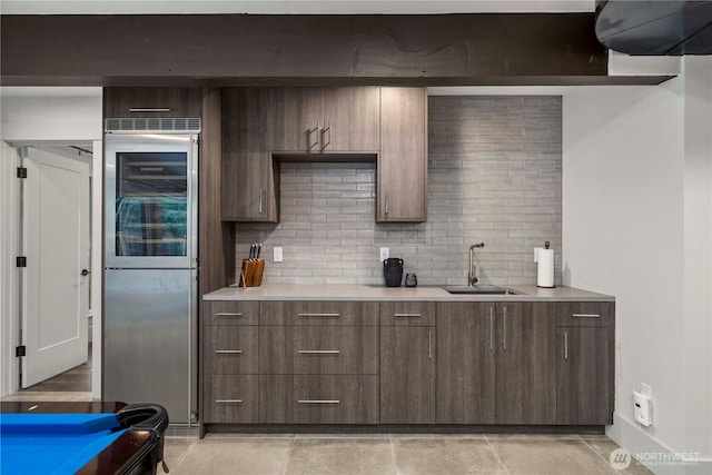 kitchen featuring light countertops, wine cooler, tasteful backsplash, and a sink