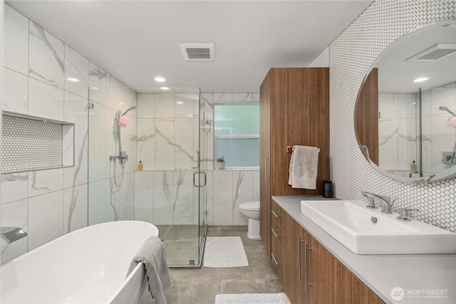 full bath featuring a marble finish shower, visible vents, toilet, a freestanding bath, and tile walls