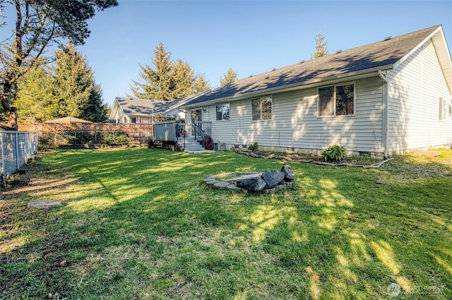 back of property with crawl space, a fenced backyard, and a yard