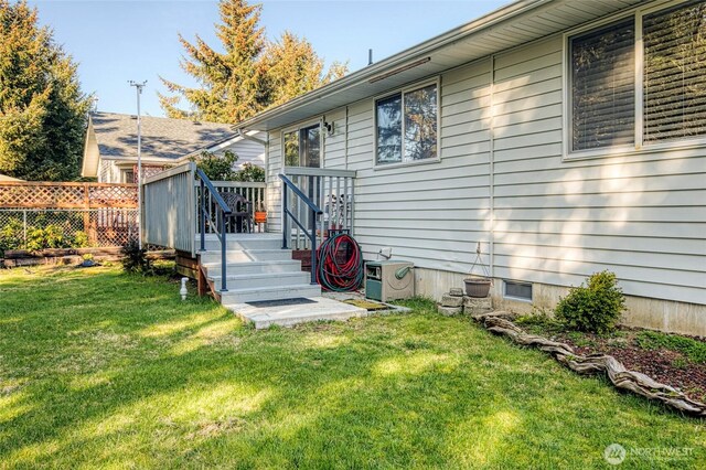 back of house with a deck, a lawn, and fence