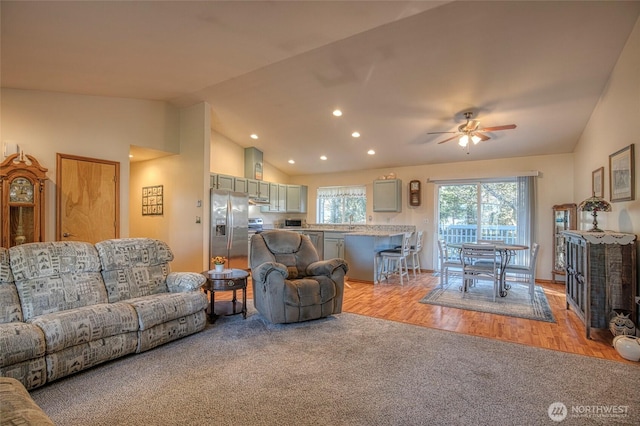 living room with ceiling fan, recessed lighting, light carpet, light wood-style floors, and vaulted ceiling