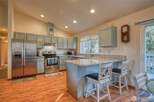 kitchen featuring stainless steel appliances, light wood-type flooring, a peninsula, and under cabinet range hood