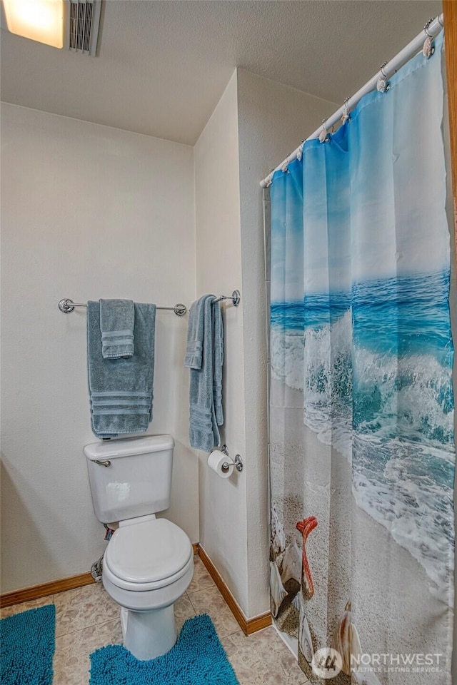 full bath with baseboards, a shower with shower curtain, a textured ceiling, and toilet