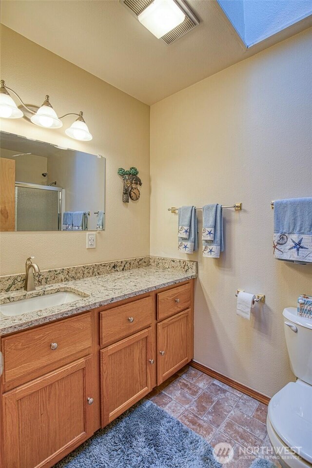 bathroom featuring visible vents, toilet, a shower stall, and vanity